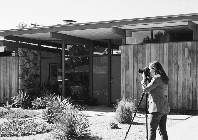 A real estate agent photographing a house exterior on a tripod