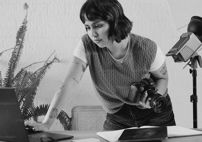 A woman adjusting a camera on a tripod in a plant-filled room