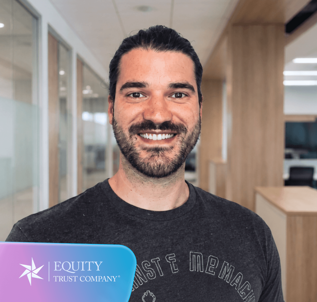 Smiling man with a beard in a grey T-shirt in an office setting, with the Equity Trust Company logo in the corner.