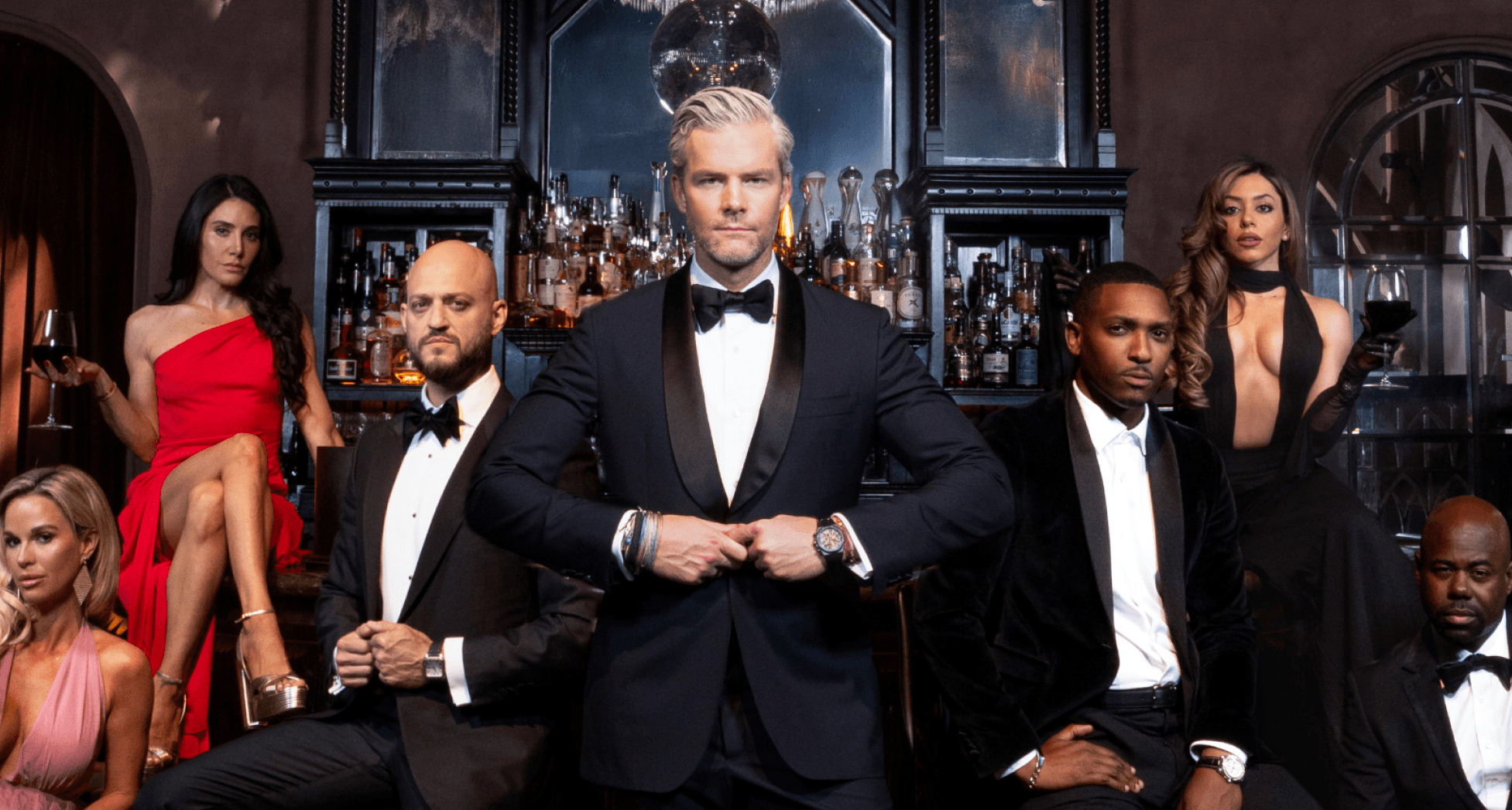 Seven formally dressed men and women pose in a sophisticated bar.