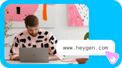 男性がノートパソコンで作業しており、チャットの吹き出しに「www.heygen.com」と表示されている。