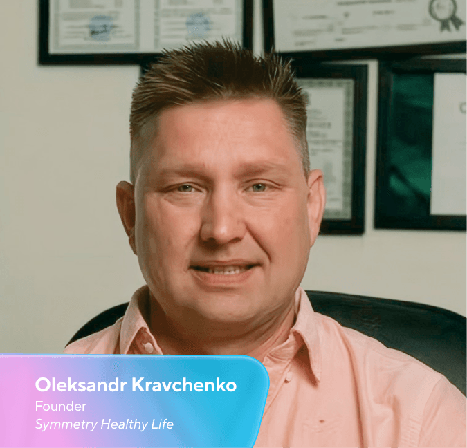 Oleksandr Kravchenko, Founder of Symmetry Healthy Life, smiling and wearing a light pink shirt.