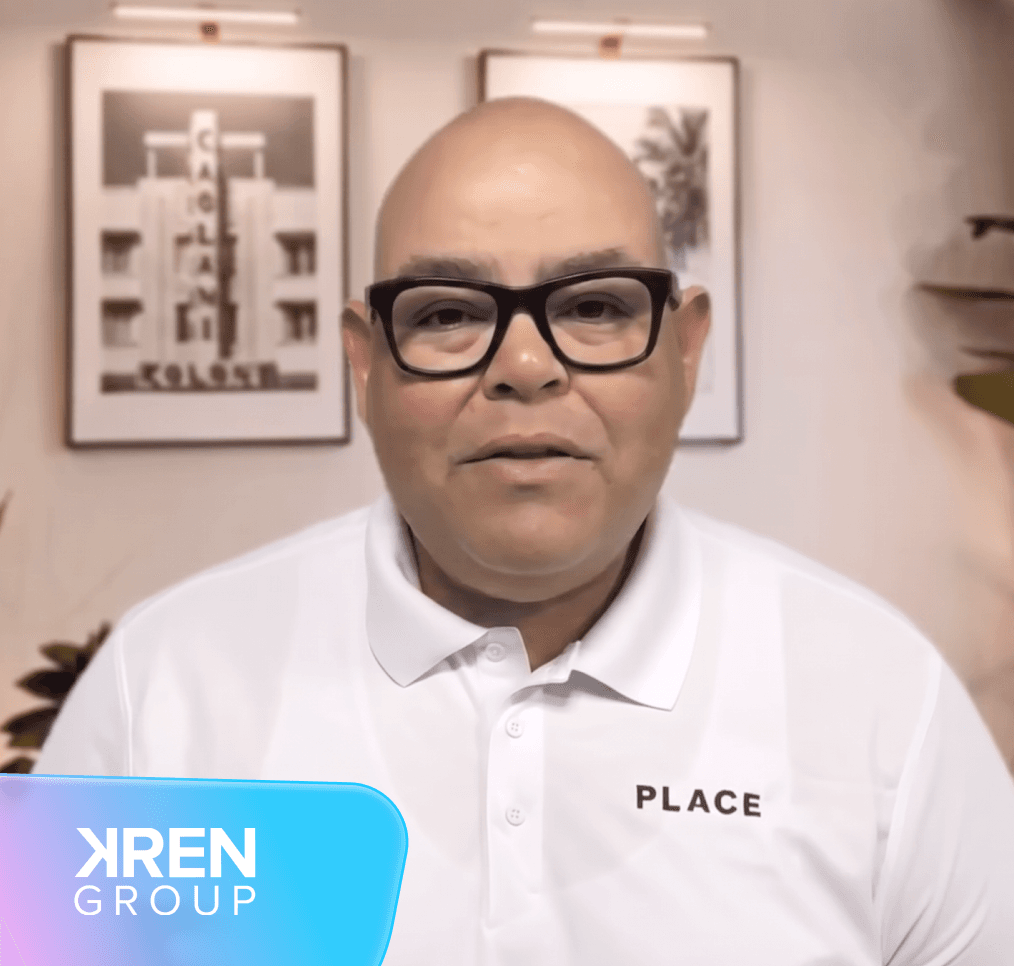 Bald man in glasses wearing a white "PLACE" polo shirt, with framed art and a plant in the background. "KREN GROUP" logo at bottom left.